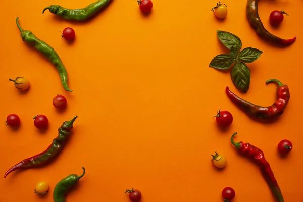 Draufsicht auf frische reife Tomaten und Chilischoten auf orangefarbenem Hintergrund — Stockfoto