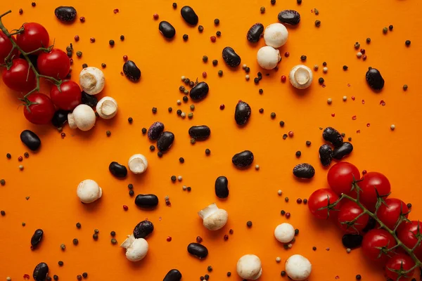 Blick von oben auf frische Champignon-Champignons, Tomaten, Pfefferkörner und Haricot-Bohnen auf Orange — Stockfoto