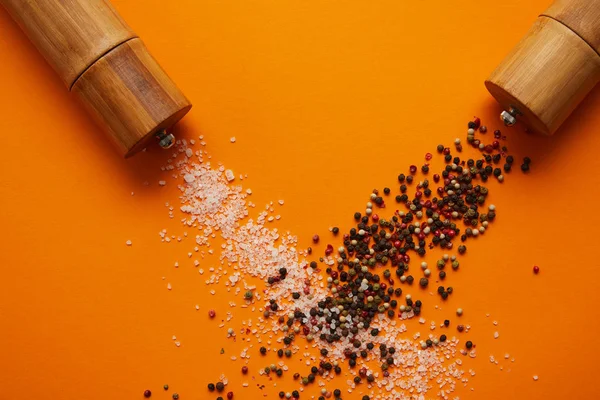 Blick von oben auf Gewürzbehälter und Salz mit Pfefferkörnern auf Orange — Stockfoto