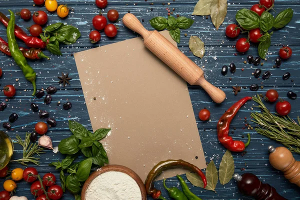 Top view of fresh raw vegetables, spices, blank card and rolling pin on wooden surface — Stock Photo