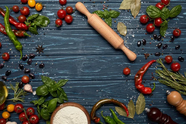 Top view of fresh raw vegetables, spices and rolling pin on wooden surface — Stock Photo