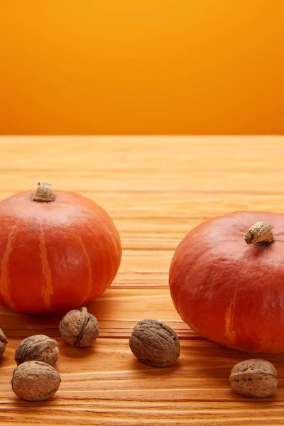 Vue rapprochée des citrouilles fraîches mûres et des noix sur la surface en bois — Photo de stock