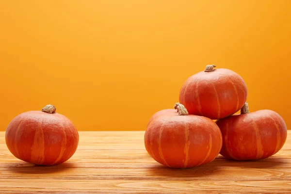 Zucche mature fresche su superficie di legno su fondo arancione — Foto stock