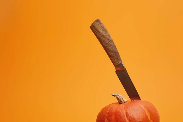 Close-up view of ripe pumpkin with knife isolated on orange background — Stock Photo