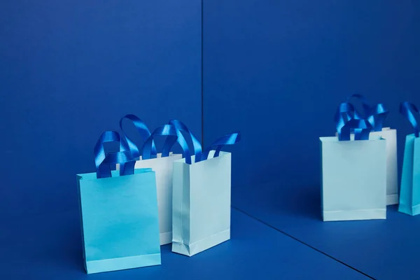 Vue rapprochée des sacs à provisions en papier disposés avec miroir réfléchissant sur fond bleu — Photo de stock