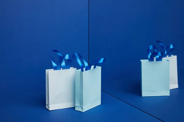 Vue rapprochée des sacs à provisions en papier disposés avec miroir réfléchissant sur fond bleu — Photo de stock