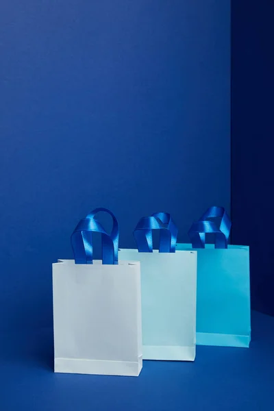 Vista de cerca de bolsas de compras de papel dispuestas sobre fondo azul - foto de stock