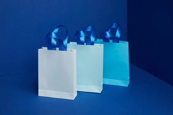 Vista de perto de sacos de compras de papel dispostos em fundo azul — Fotografia de Stock