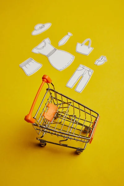 Закрытый вид на маленькие магазинчики и одежду из бумаги на желтом фоне — стоковое фото