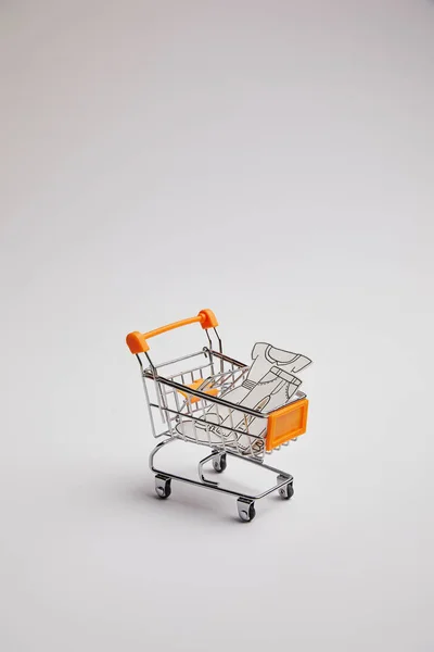 Vista de perto do carrinho de compras com pequenas mercadorias feitas de papel sobre fundo cinza — Fotografia de Stock