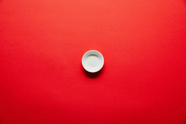 Vista superior de tigela vazia branca para molho de soja no fundo vermelho — Fotografia de Stock