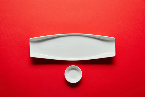 Vue du dessus de la plaque blanche vide et bol pour sushi sur fond rouge — Photo de stock