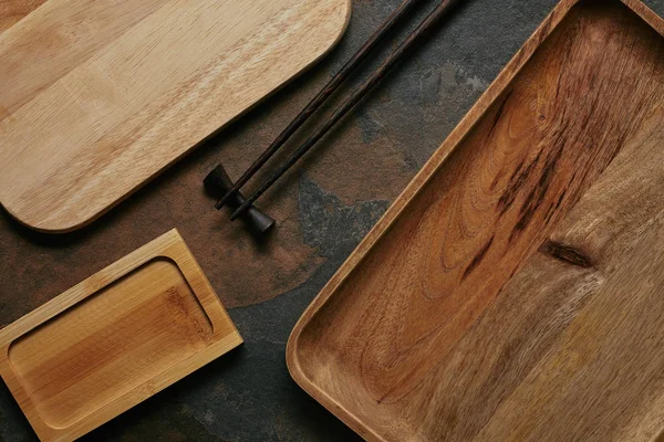 Tendido plano con platos de madera vacíos y palillos para sushi en la mesa oscura — Stock Photo