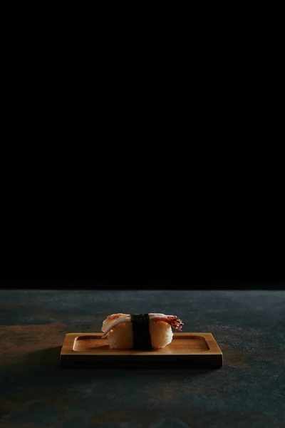 Close up view of nigiri sushi with shrimp on wooden plate on black background — Stock Photo