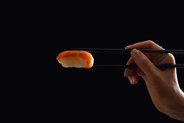 Cortado quente de mulher segurando nigiri sushi com salmão isolado em preto — Fotografia de Stock