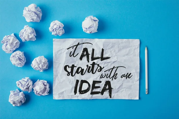 Top view of crumpled papers and pencil on blue surface with 