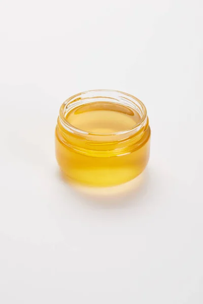 Close up view of sweet organic honey in glass jar on white surface — Stock Photo