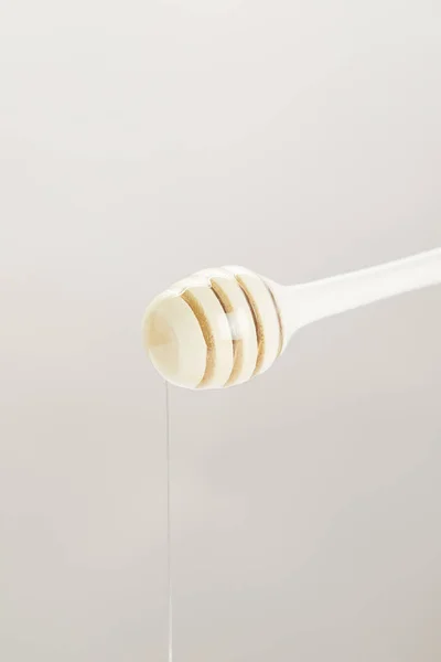 Close up view of wooden honey deeper with organic honey on grey background — Stock Photo