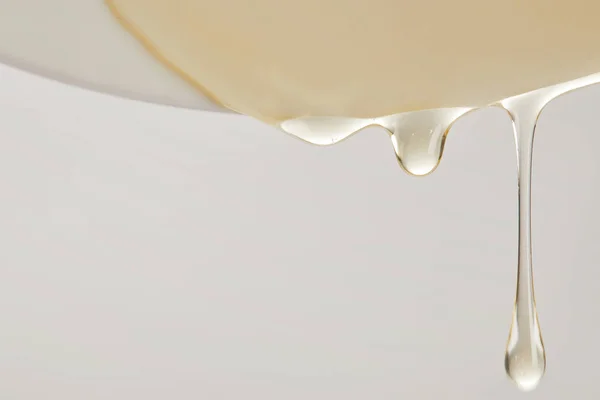 Close up view of honey flowing from white plate on grey background — Stock Photo