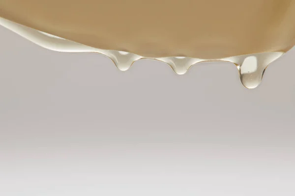 Close up view of honey flowing from white plate on grey background — Stock Photo