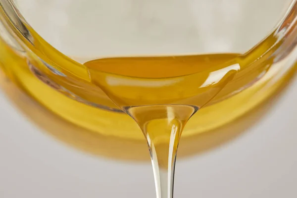 Vista de cerca de la miel dulce que fluye del frasco de vidrio - foto de stock