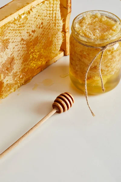 Close up view of wooden honey deeper, glass jar with honey and stack of beeswax on white tabletop — Stock Photo