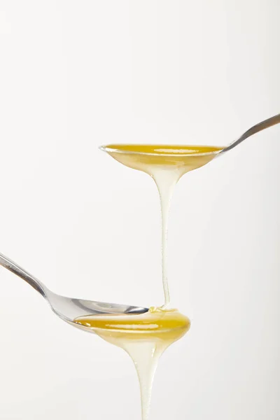 Vista de cerca de cucharas con miel sobre fondo blanco - foto de stock