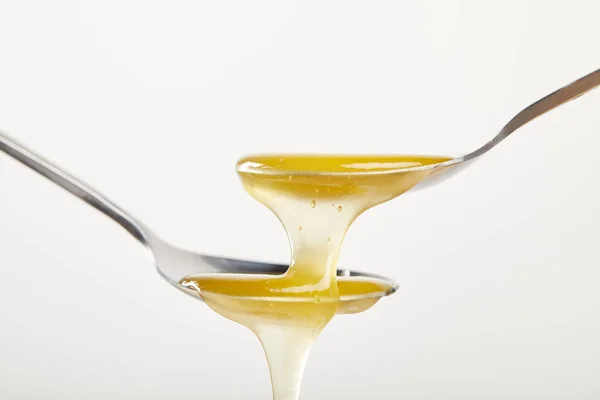 Vista de cerca de cucharas con miel sobre fondo blanco - foto de stock