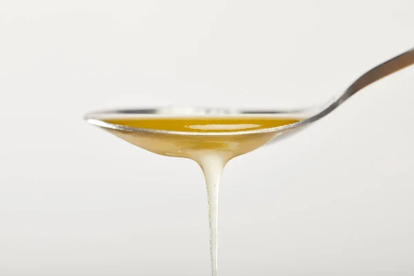 Vue rapprochée de la cuillère avec du miel naturel sur fond gris — Photo de stock