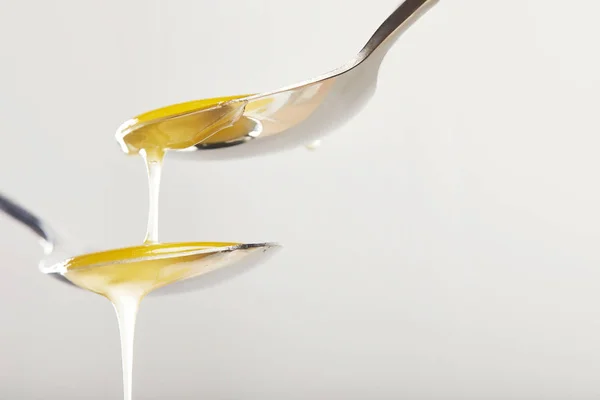 Close up view of spoons with honey on grey background — Stock Photo