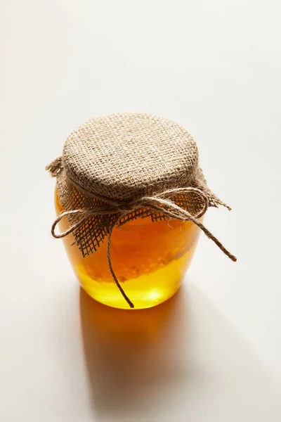 Close up view of honey and beeswax in glass jar on white surface — Stock Photo