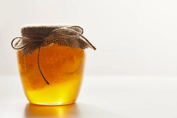 Vista de cerca de la miel y la cera de abejas en frasco de vidrio sobre fondo blanco - foto de stock