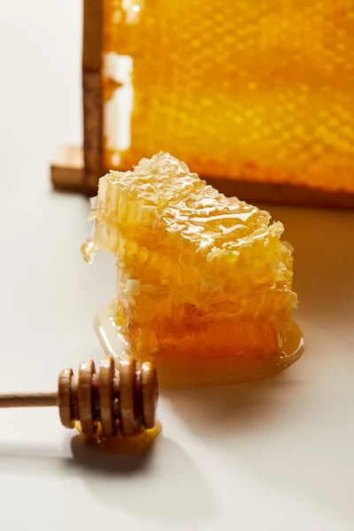 Vista da vicino del miele di legno più profondo e pila di cera d'api su un tavolo bianco — Foto stock
