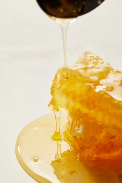 Vista de perto de cera de abelha e derramamento de mel processo no fundo branco — Fotografia de Stock