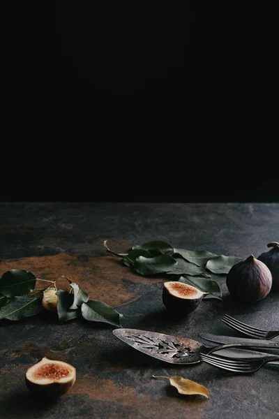 Close up view of antique cutlery, green leaves and figs on grungy surface — Stock Photo