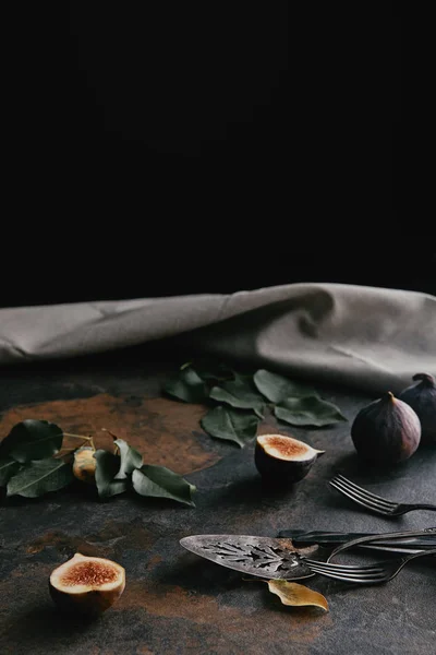 Close up view of antique cutlery, green leaves and figs on grungy surface — Stock Photo