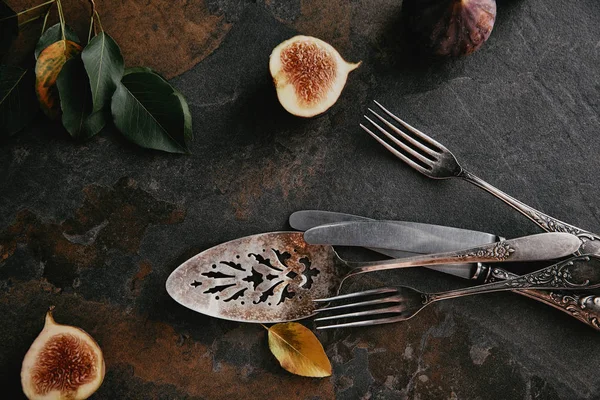 Top view of antique cutlery, green leaves and figs on grungy surface — Stock Photo