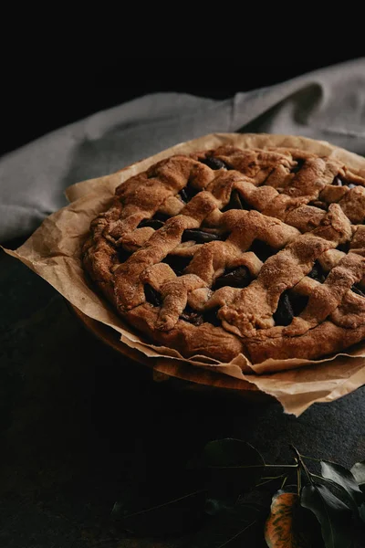 Close up view of homemade pie on baking paper on dark background — Stock Photo