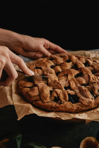 Plan recadré de femme coupant tarte sur papier cuisson avec couteau — Photo de stock