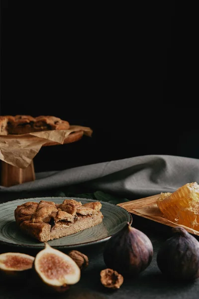 Vue rapprochée de tarte cuite au four, cire d'abeille et figues disposées sur une surface sombre — Photo de stock