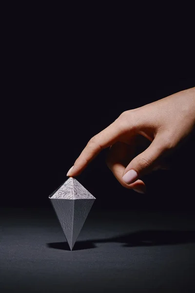 Cropped shot of hand touching faceted piece of silver mineral on black — Stock Photo