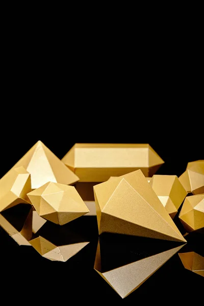 Shiny faceted golden nuggets reflected on black — Stock Photo