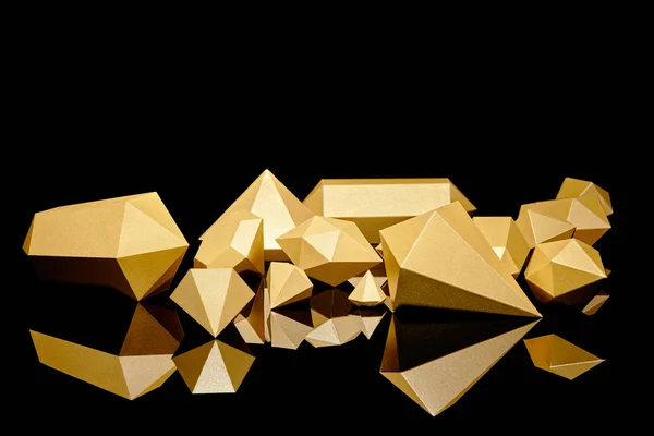 Glänzende, facettierte Goldstücke, die sich auf Schwarz spiegeln — Stockfoto