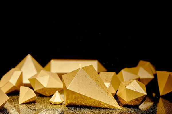 Vista close-up de pedaços facetados brilhantes de ouro e poeira dourada refletida no preto — Fotografia de Stock