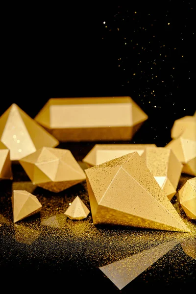 Vista de cerca de brillantes piezas brillantes de oro y polvo dorado en negro - foto de stock