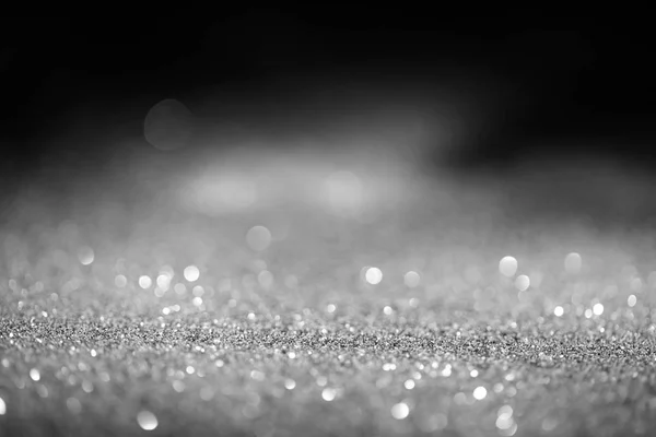 Abstract blurred glowing silver glitter on dark background — Stock Photo