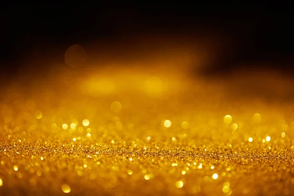 Abstract blurred golden glitter on dark background — Stock Photo