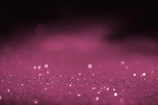 Abstract blurred pink glitter on dark background — Stock Photo