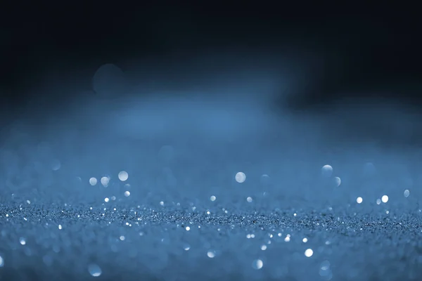 Blurred blue glowing glitter on black background — Stock Photo