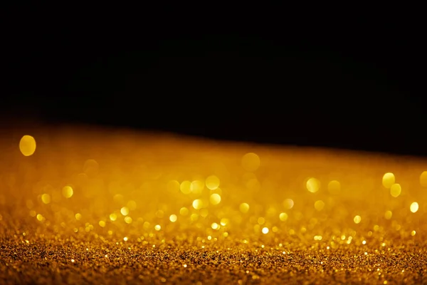 Blurred golden glowing glitter on black background — Stock Photo